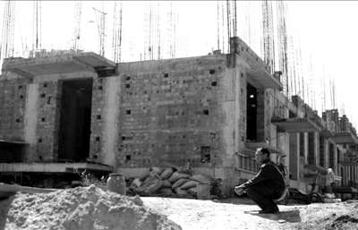 买房村民蹲在被定性为违建的楼房前一脸无奈