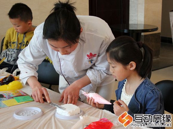 图为烘焙师帮助小朋友美化蛋糕坯