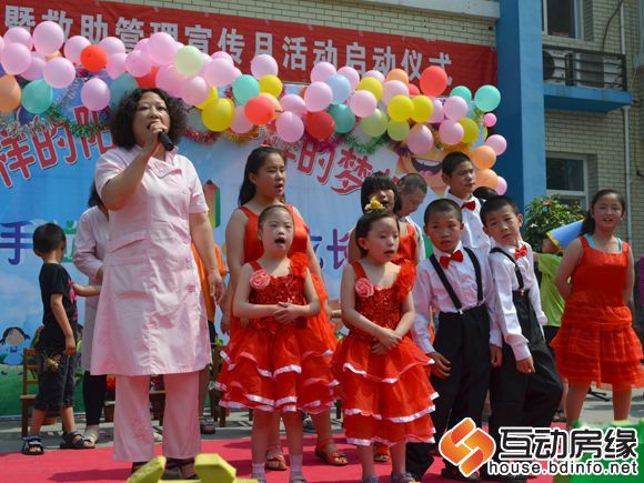 图为福利院工作人员和孩子一起表演节目
